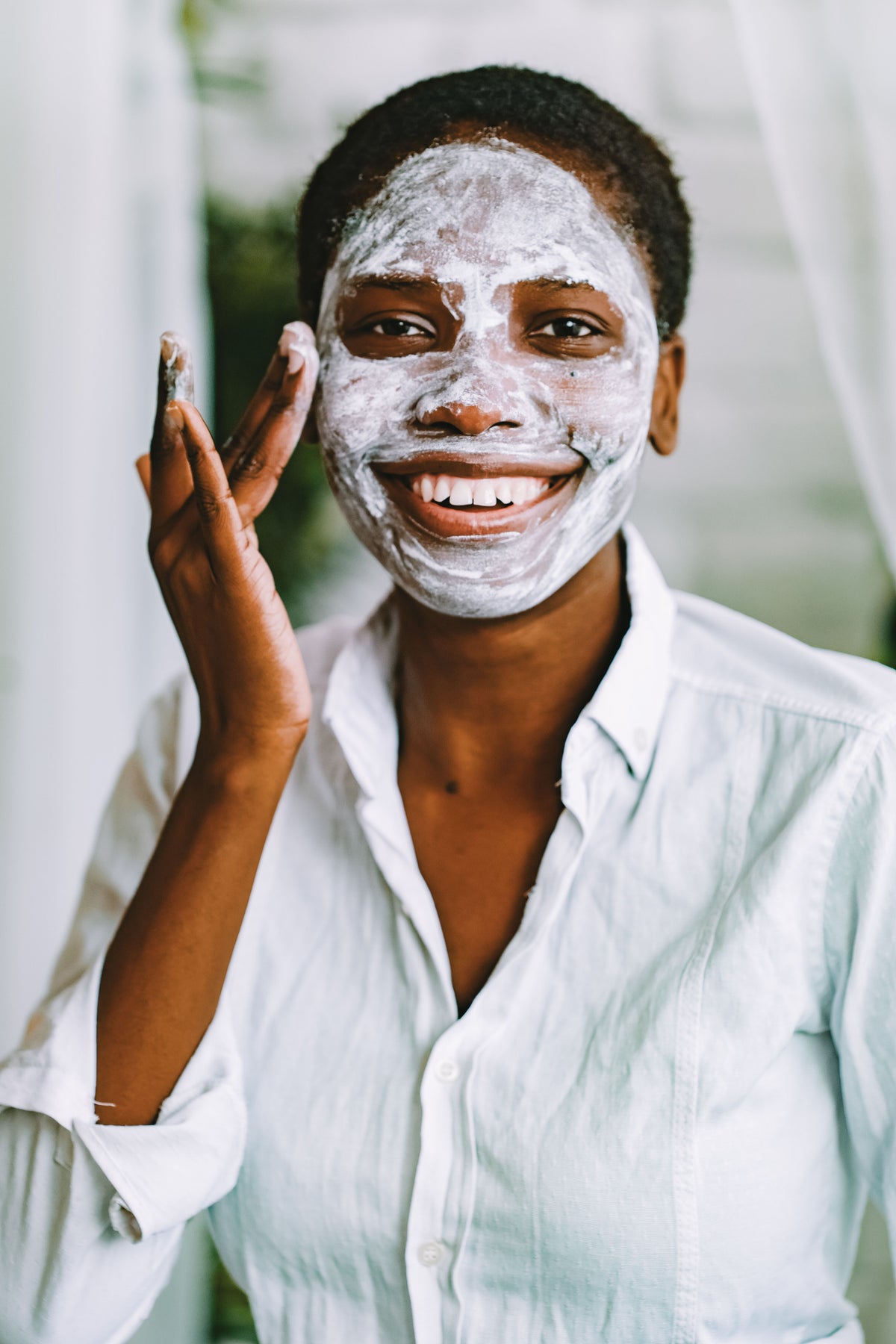INTÉRÊT — Femme noire appliquant son masque soin visage avec joie, routine beauté naturelle
